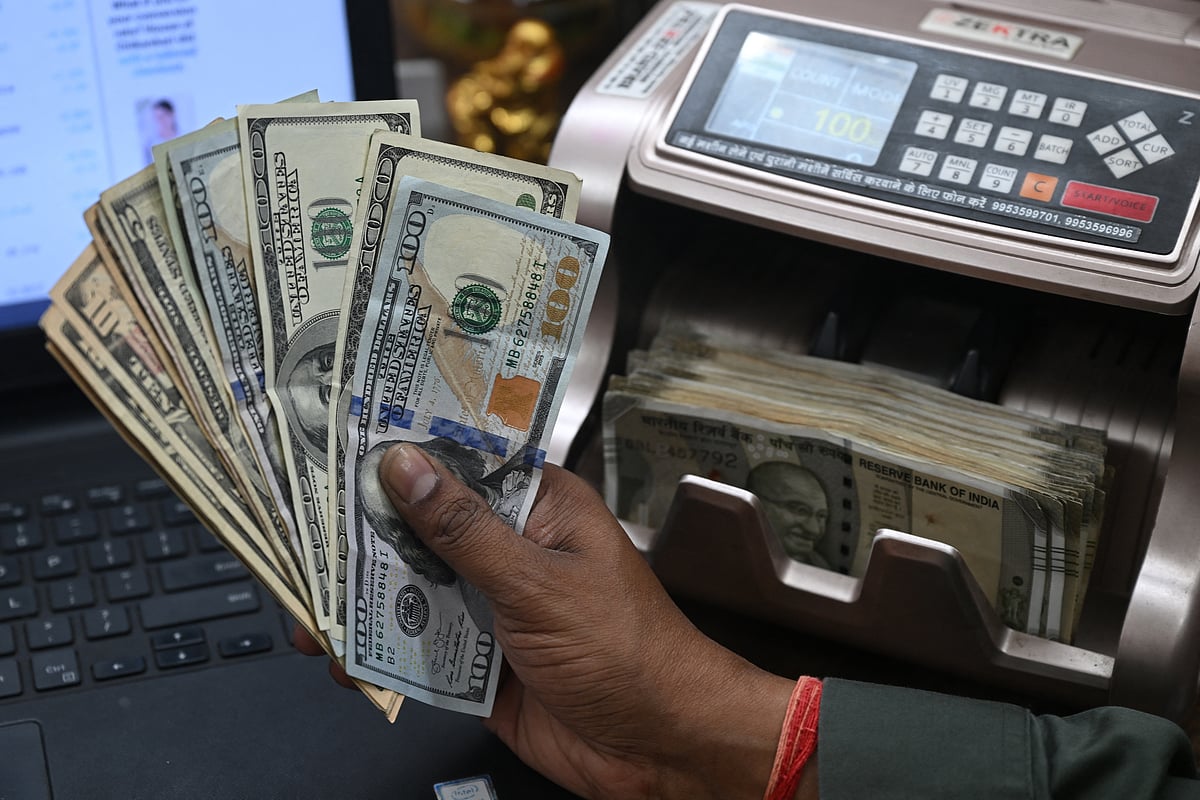 A worker holding US dollars banknotes poses for a photograph at a money exchange outlet in New Delhi on April 3, 2025.